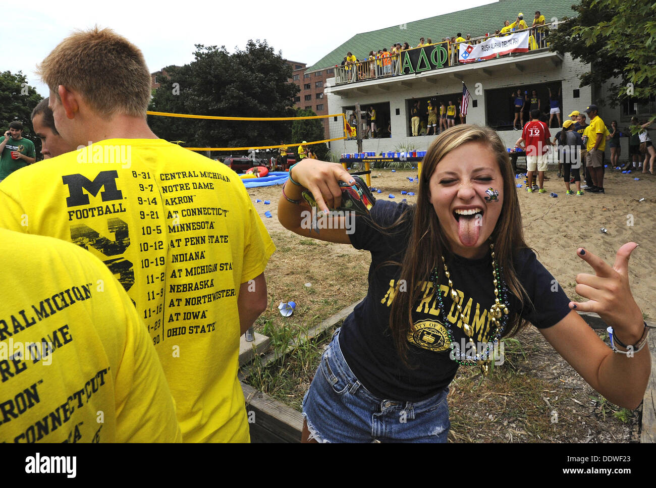 Aug. 7, 2013 - Ann Arbor, Michigan, U.S - The University of Michigan football schedule is displayed on the back of a guy's shirt as a Notre Dame fan hams it up for the camera a few hours before the start of the football game in Ann Arbor, MI on Sept 7, 2013.  In background, people at the Alpha Delta Phi frat house party it up. (Credit Image: © Mark Bialek/ZUMAPRESS.com) Stock Photo