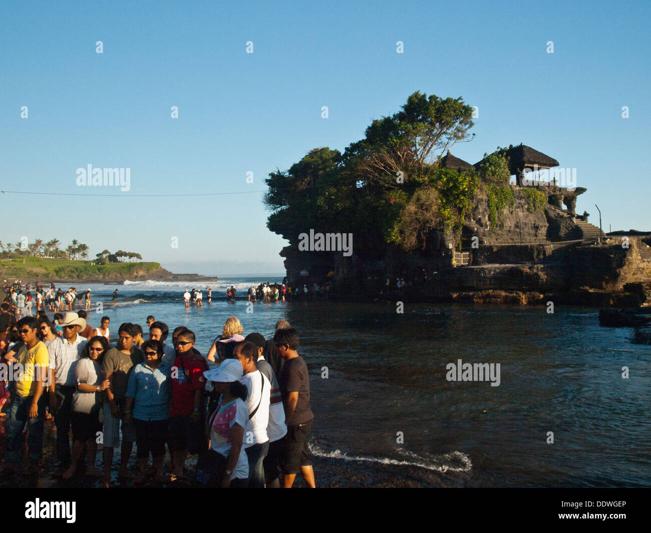 Balinese pilgrims taking pictures in front of Tanah Lot temple Stock Photo