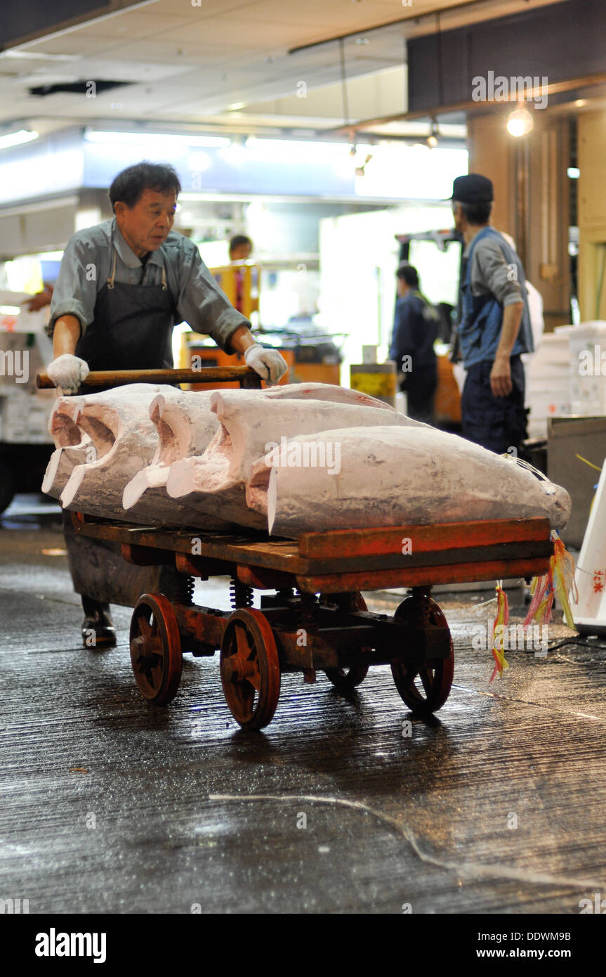 A worker at a fish market in Osaka, Japan pushing a cart with frozen