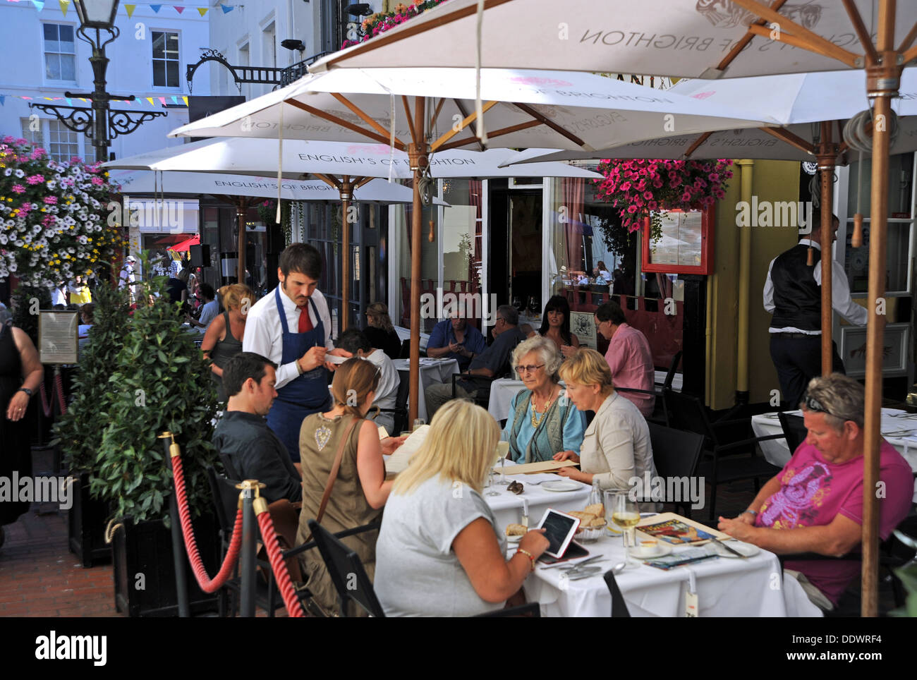 Waiter serving customers at English's seafood and oyster bar restaurant alfresco style outside in The Lanes area of Brighton UK Stock Photo