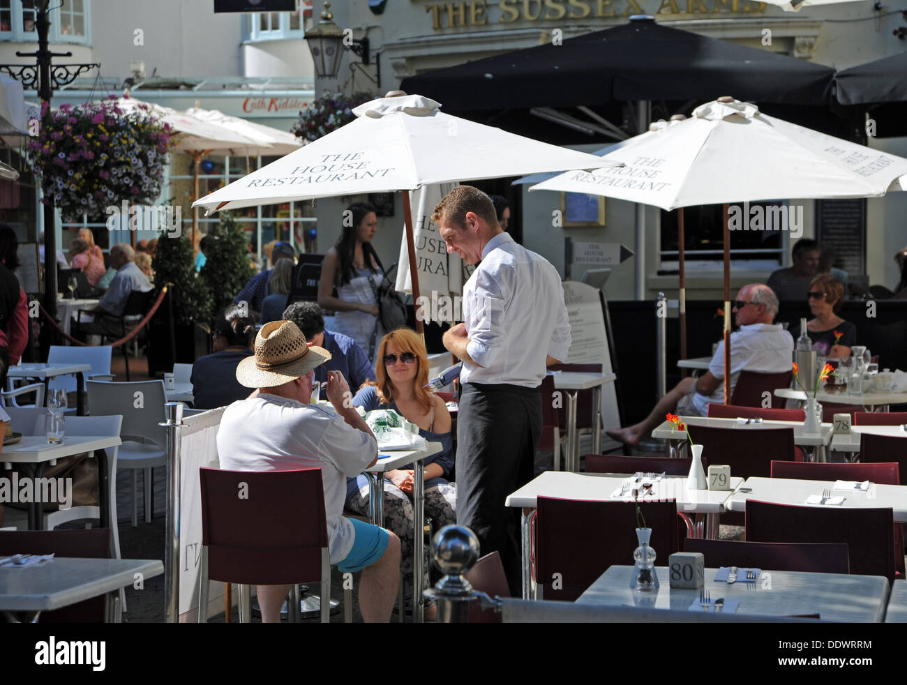 Waiter serving customers at restaurant alfresco style outside in The Lanes area of Brighton UK Stock Photo