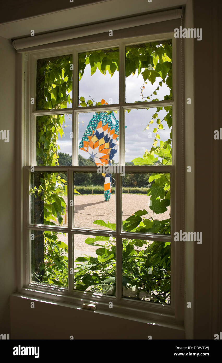 A Yinka Shonibare MBE sculpture viewed from a leafy window at Yorkshire Sculpture Park Stock Photo