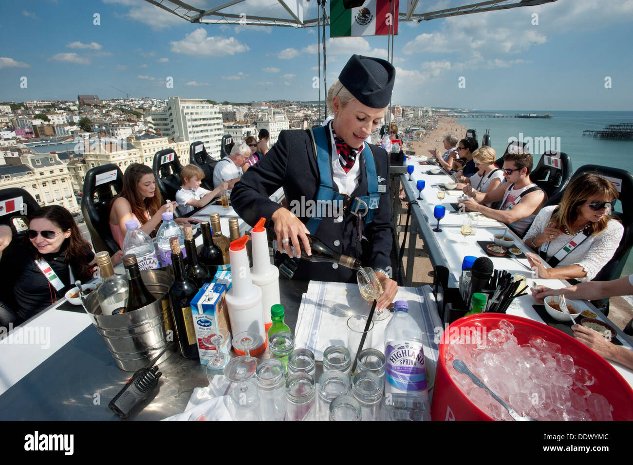 A British Airways Ambassador Stewardess Purser serving drinks to 22 diners 100 foot high in the sky above Brighton and Hove beach on a dining table in the sky. Stock Photo