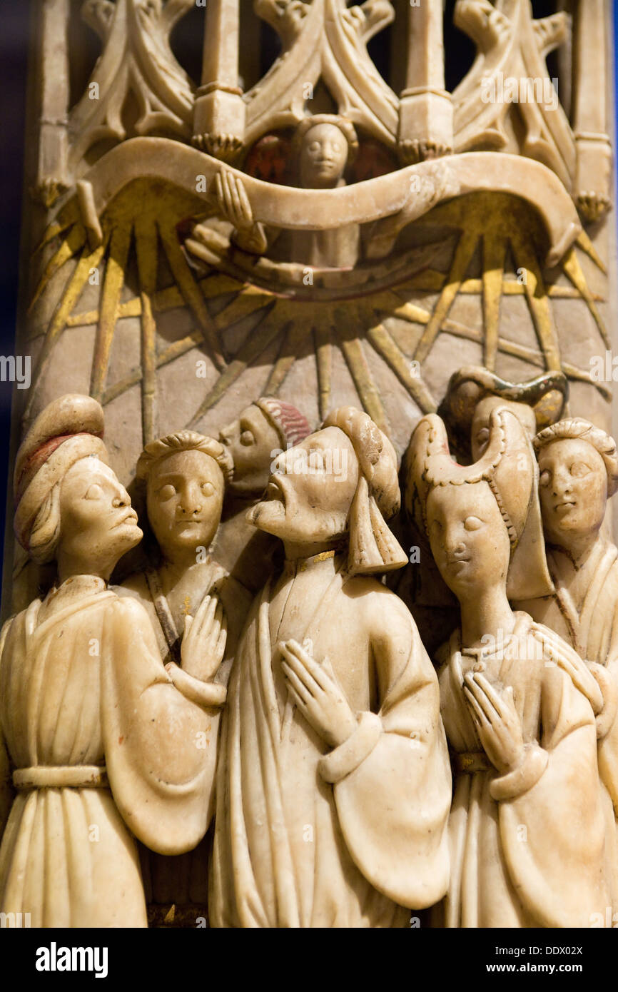 Medieval alabaster sculpture; group of devout male and female nobles in prayer, angel above holding a scroll: ivory coloured wit Stock Photo