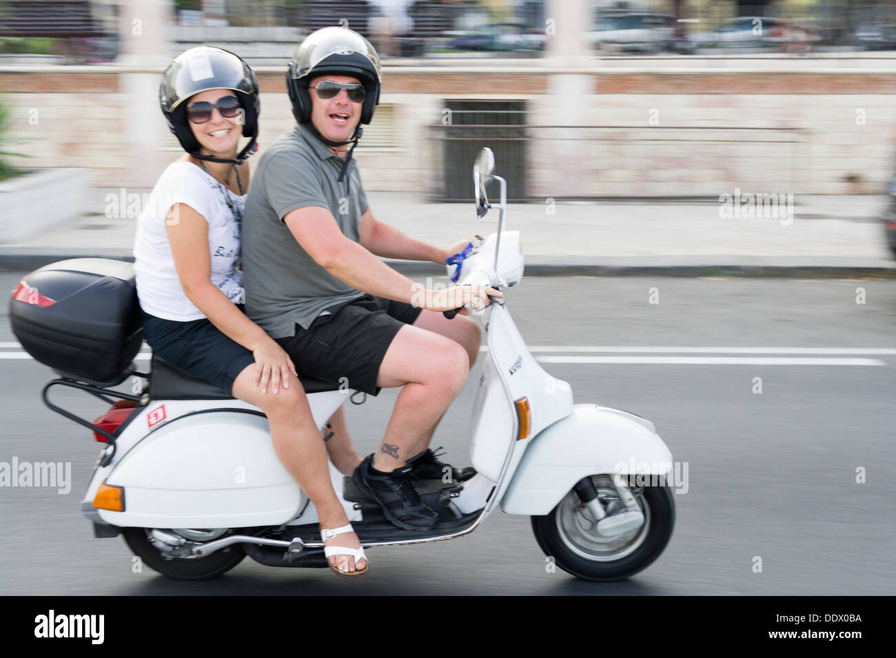 Italian La dolce Vita couple riding classic iconic vespa scooter Stock Photo