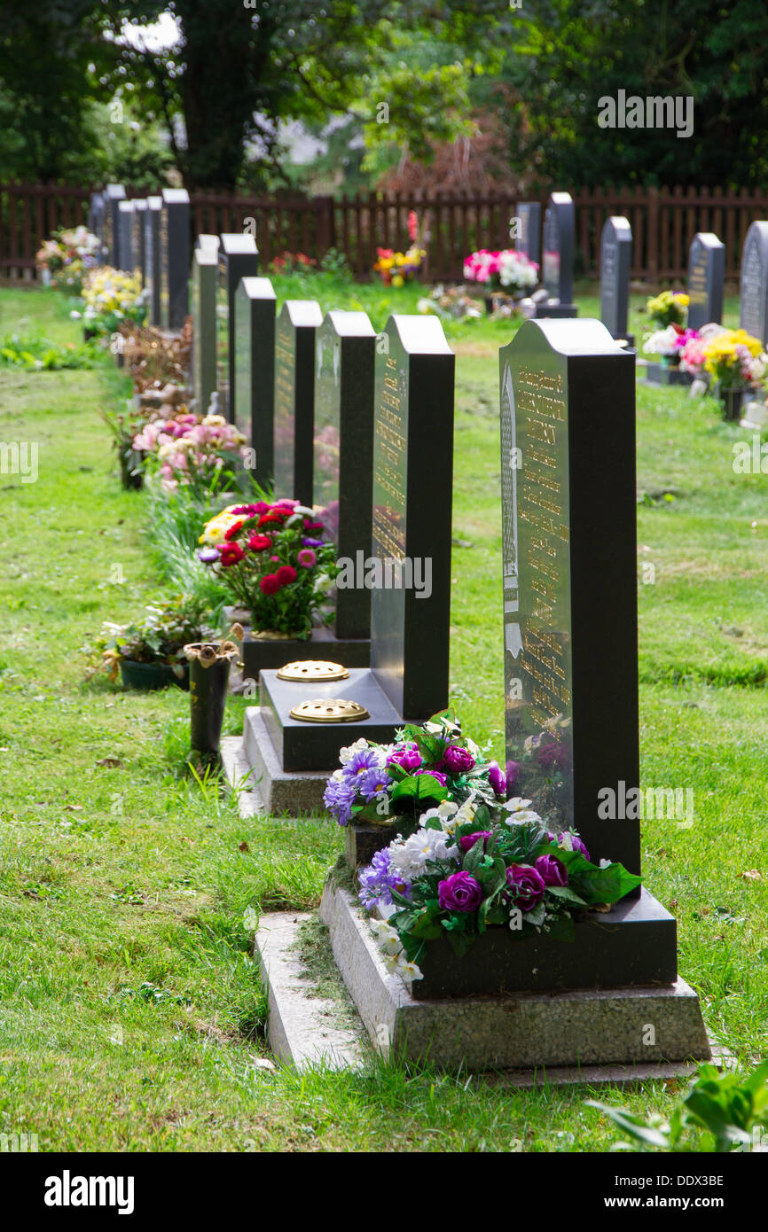 Flowers by grave stones in a cemetery. Stock Photo