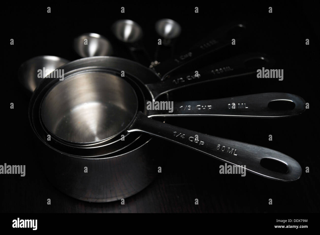 https://c8.alamy.com/comp/DDX79M/a-set-of-kitchen-measuring-cupsspoons-photographed-against-a-black-DDX79M.jpg