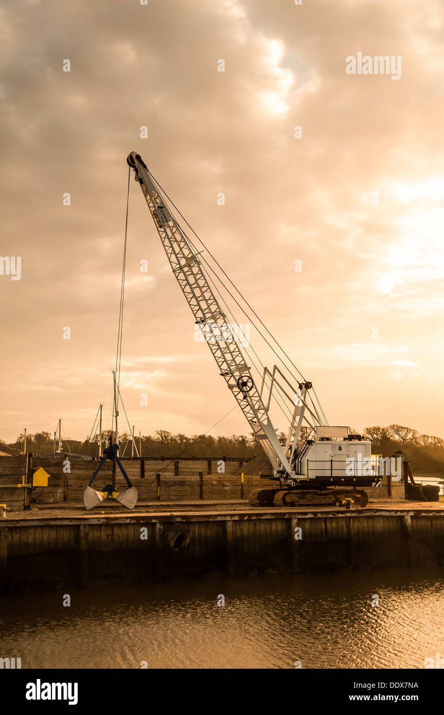 Steel crane unloading gravel to a construction material wharf Stock Photo