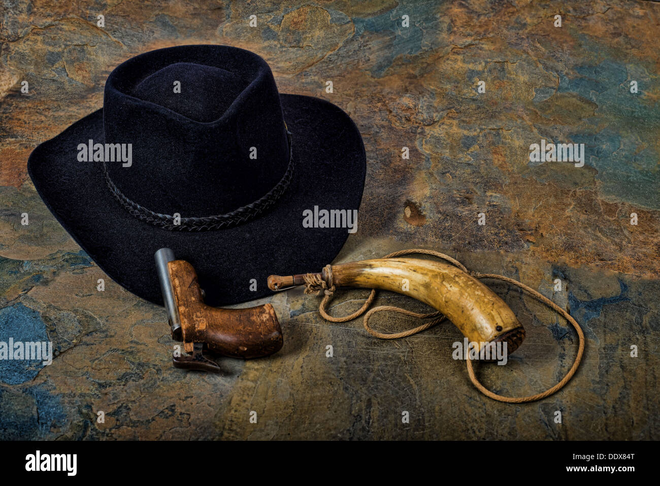 Antique pistol and powder horn with cowboy hat on slate flooring Stock Photo
