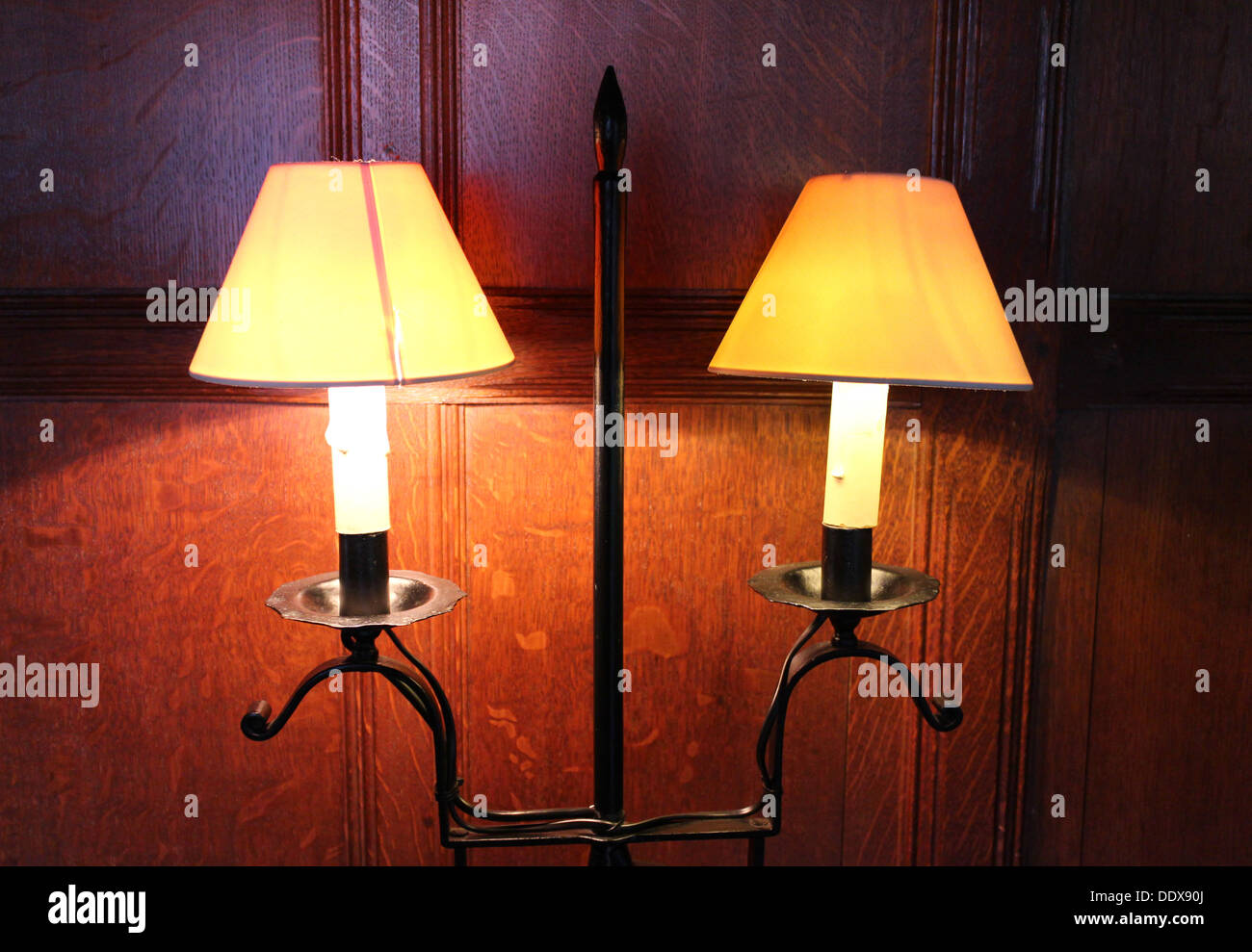 Two 1920s electric lamps wall mounted with wooden paneling in the background Stock Photo