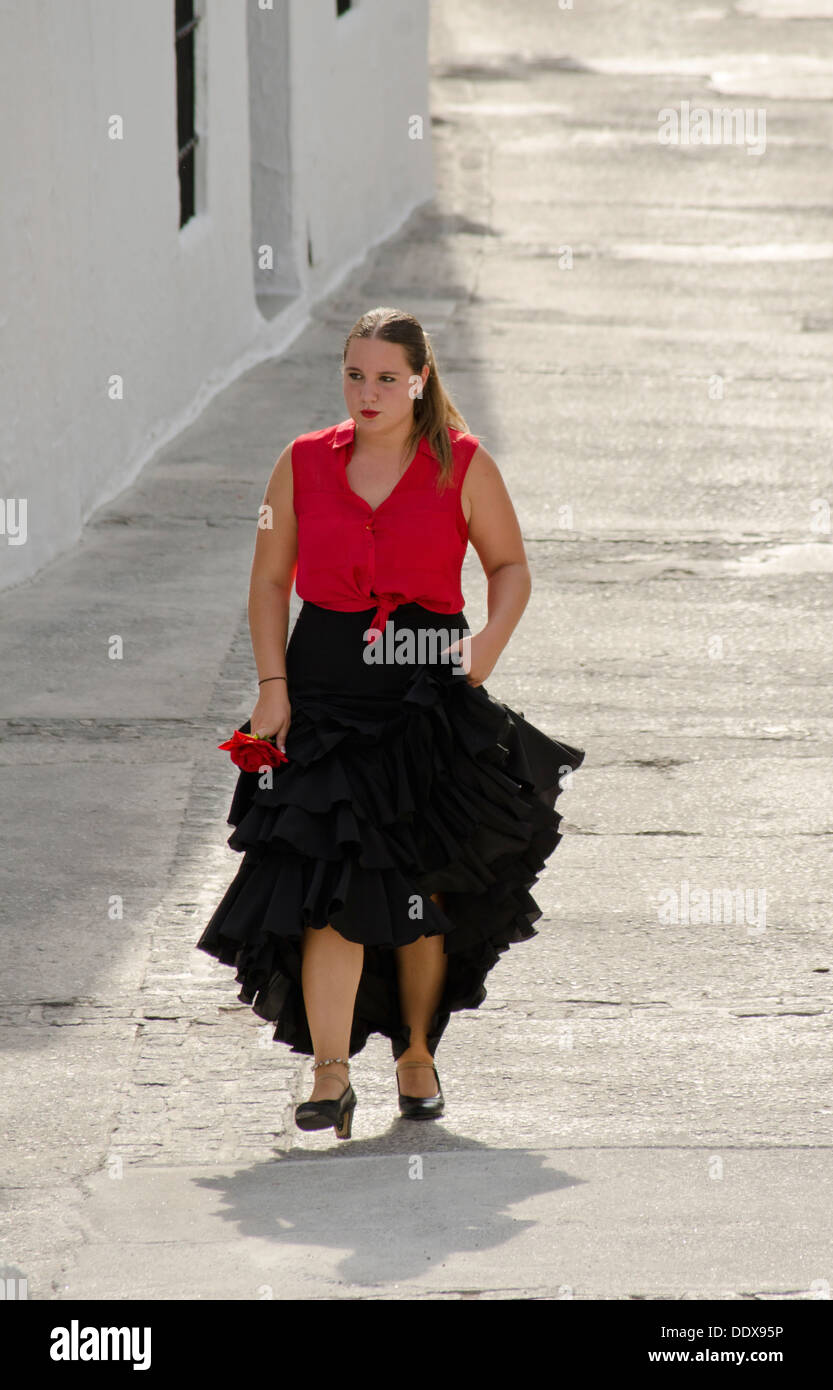 Woman in a traditional flamenco dress walking in an andalusian village. Mijas Pueblo in Southern Spain. Costa del Sol. Stock Photo