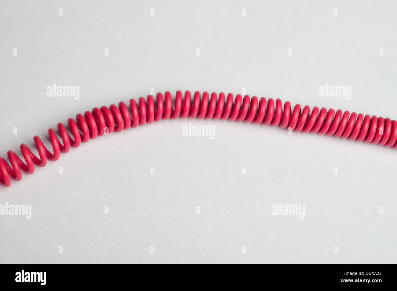 Pink phone cord on white surface Stock Photo