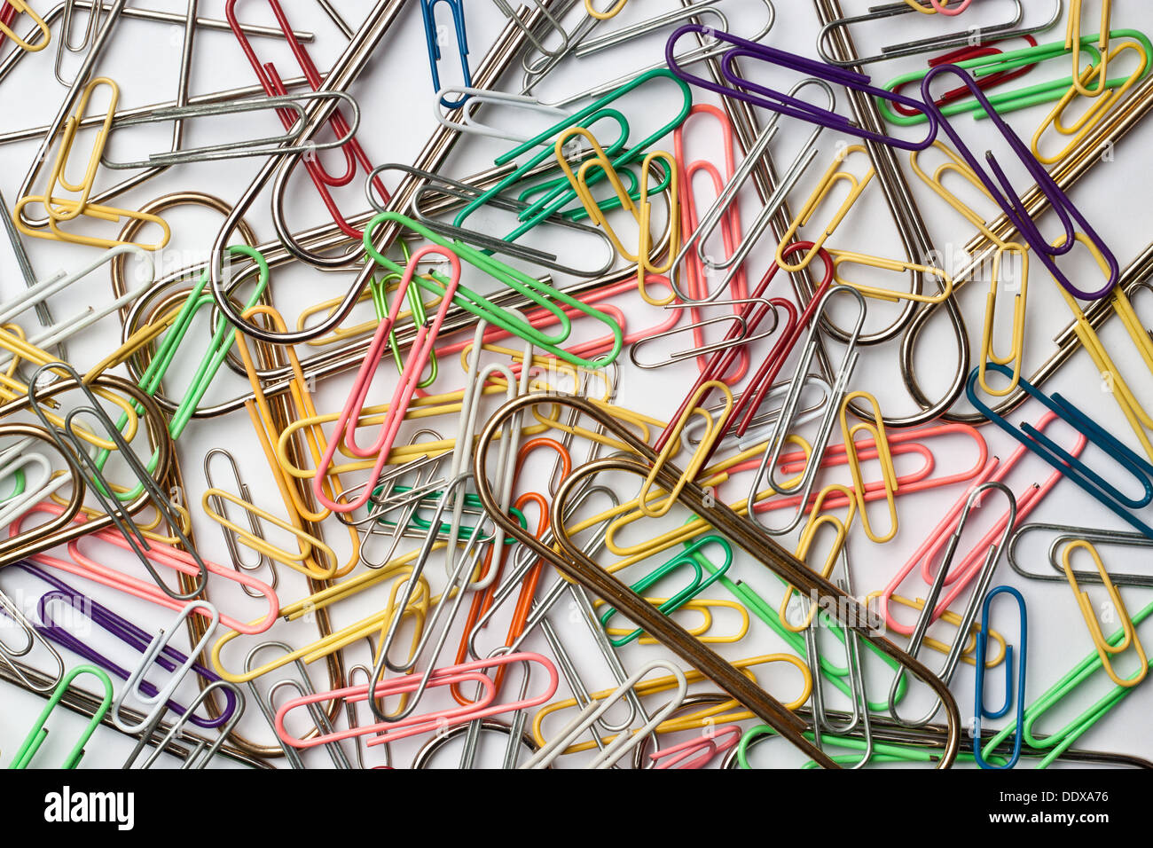 Assortment of paper clips on white surface Stock Photo