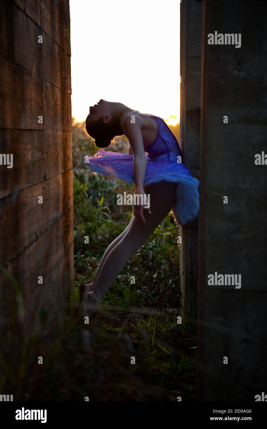 Ballerina posing in an old dilapidated building during the last hour of sunlight and as the sun sets. Stock Photo