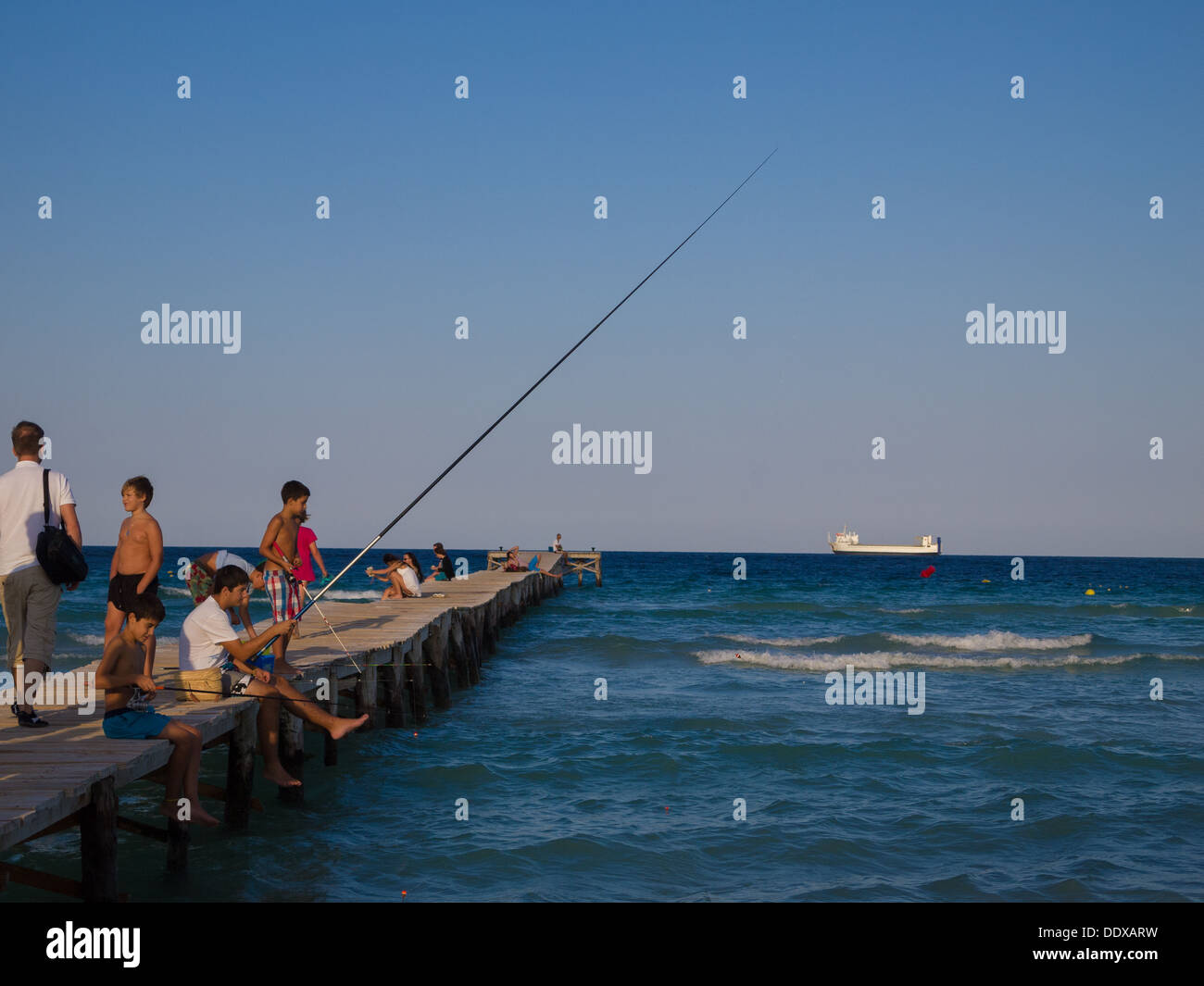 People fishing from a pier at Alcudia Beach, Mallorca Stock Photo