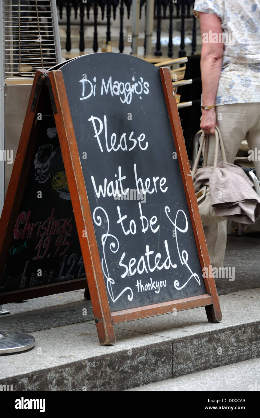 Glasgow city centre restaurant chalk board requesting patrons to 'please wait to be seated'. Stock Photo