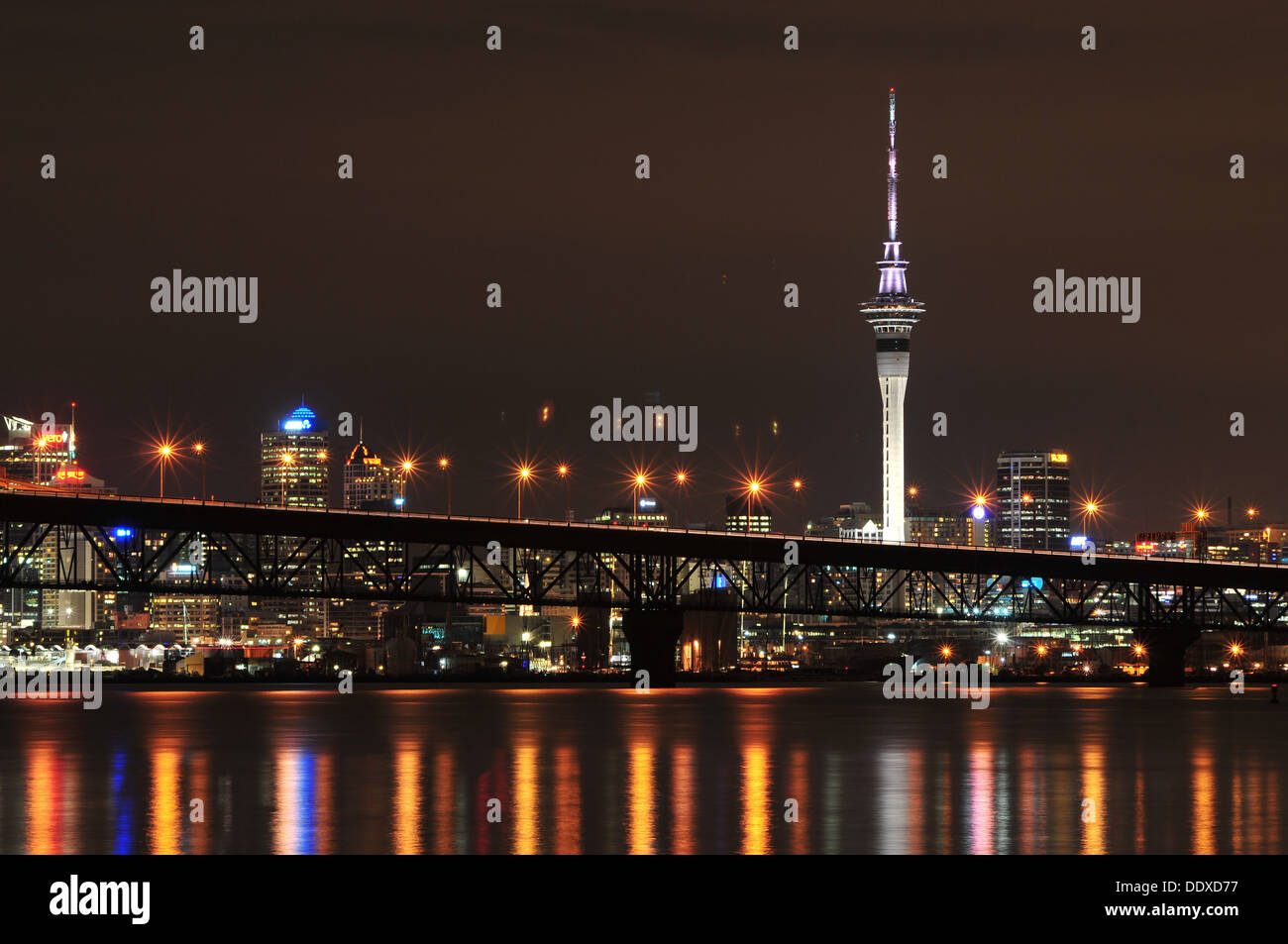 Auckland City CBD at night view from Birkenhead wharf with Harbour Bridge in foreground Stock Photo