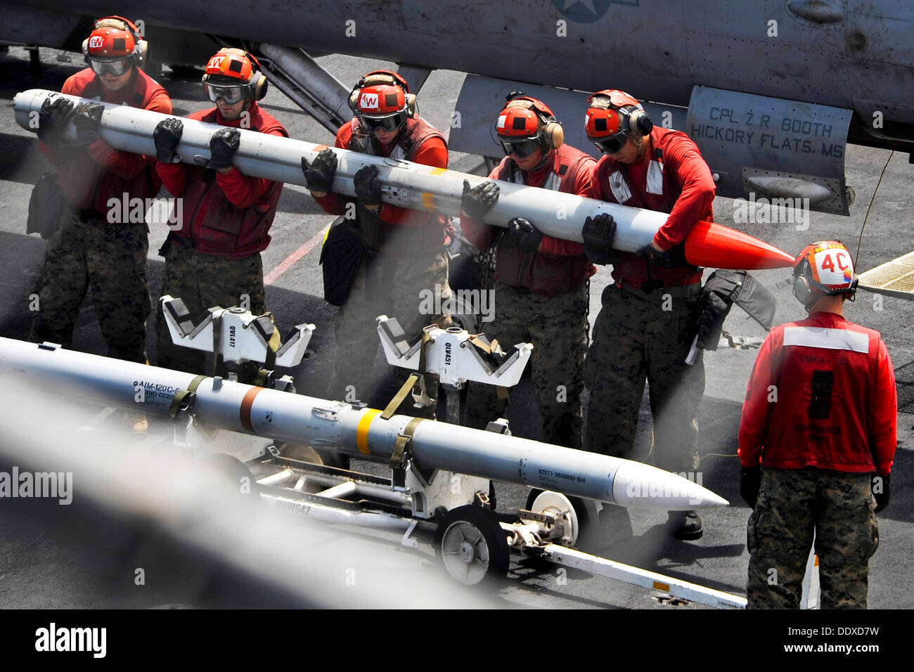 US Navy Aviation ordnancemen lift a missile on the flight deck of