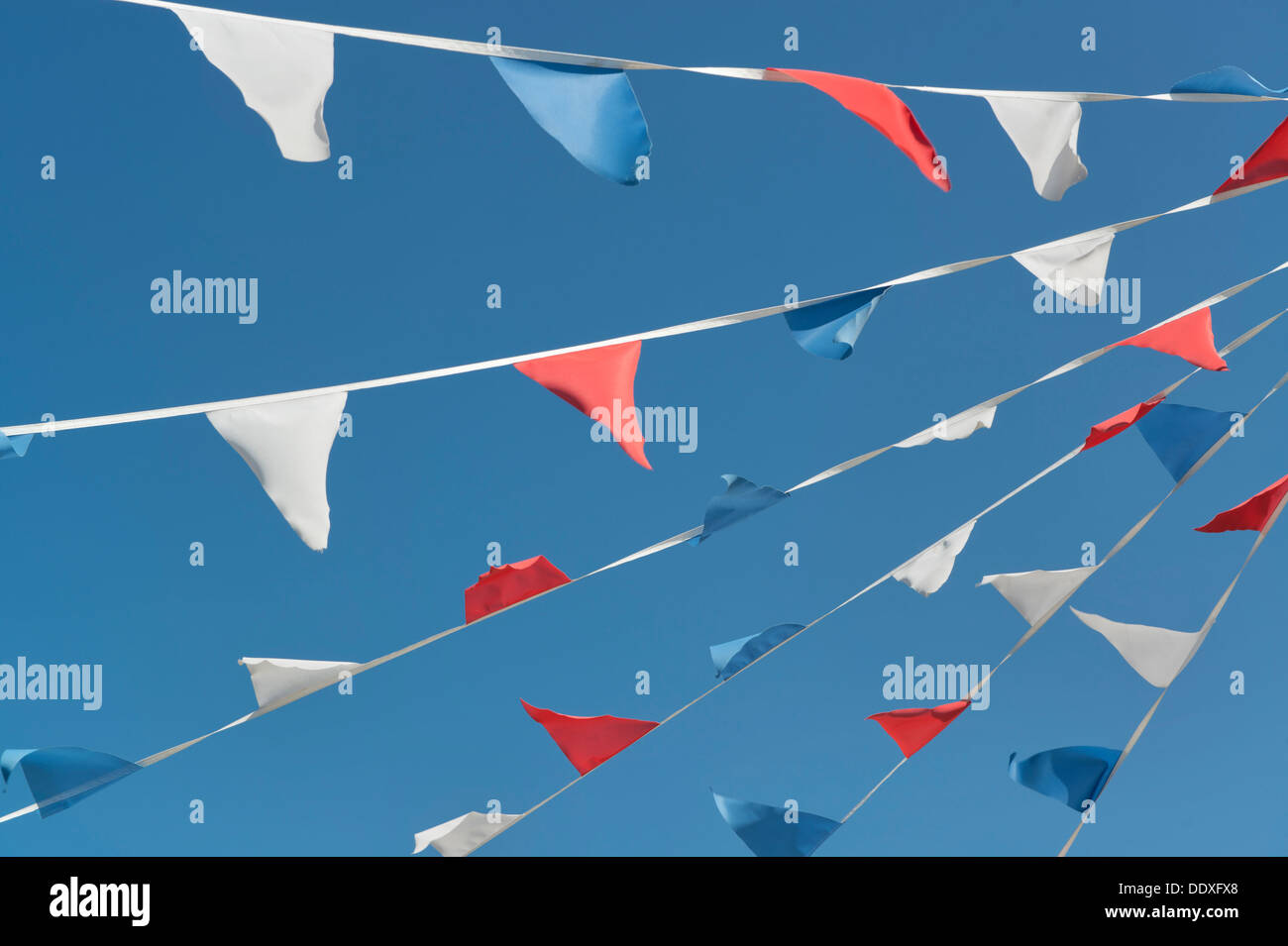 Strips of red, white and blue bunting line diagonally across a clear cloudless sky in Poole, Dorset. Stock Photo