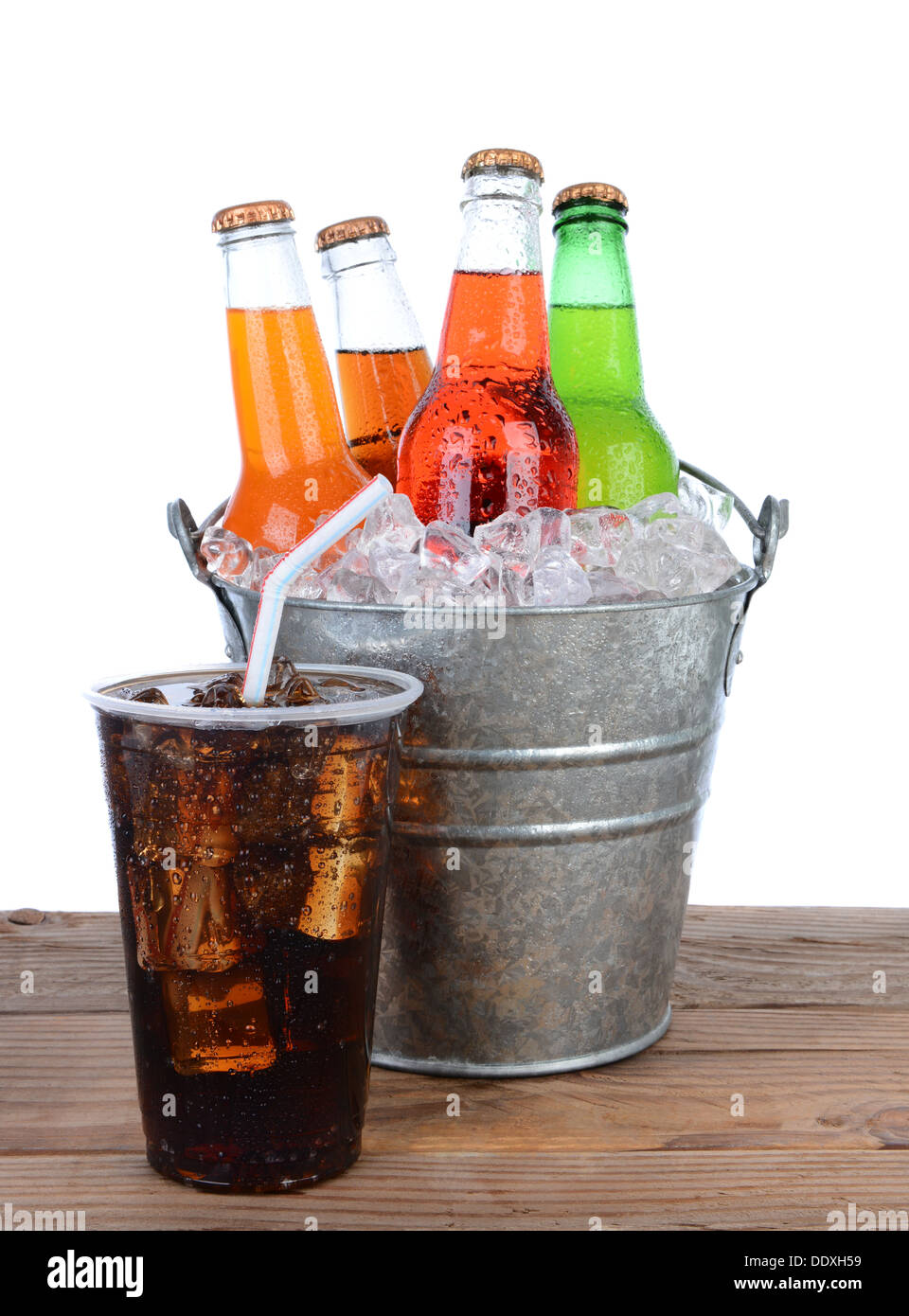 Picnic table ready for a summertime picnic. Cold soda bottles in a bucket full of ice, a full glass of cola with straw. Stock Photo