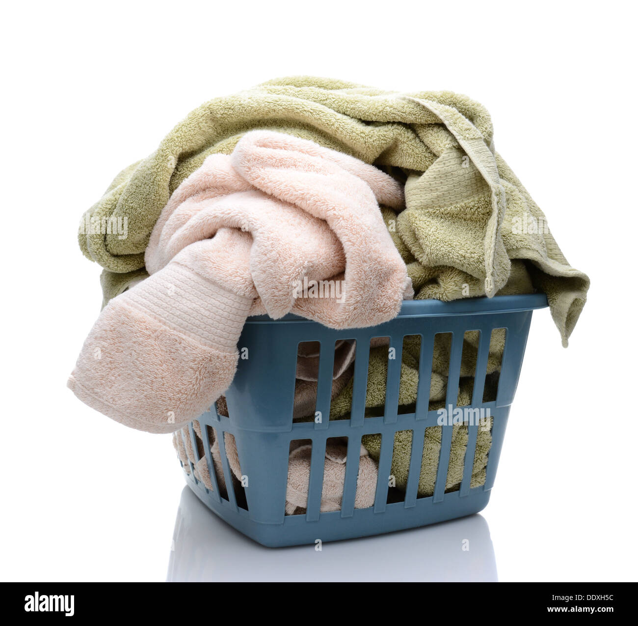 Closeup of a laundry basket full of towels. The over stuffed plastic basket is isolated on a white background with reflection. Stock Photo