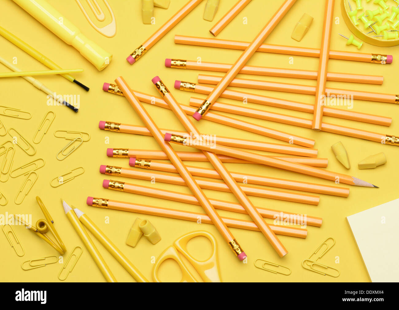 Yellow School Supplies. Pencils, erasers, paper clips, brushes, pins, scissors, paper laying in a random pattern Stock Photo