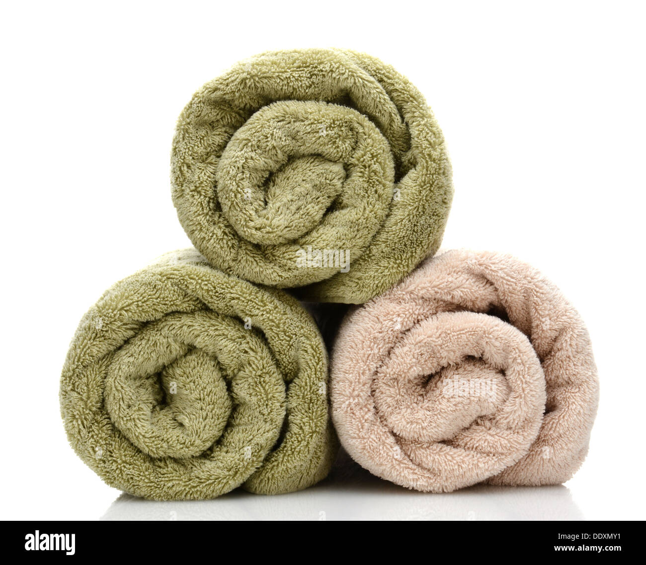 Three rolled bath towels freshly laundered on a white background with reflection. Closeup looking at the towel ends. Stock Photo