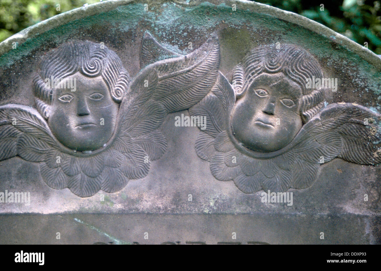 A headstone with two cherub faces. Artist Stock Photo