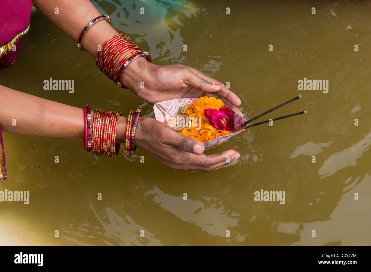 Woman offering flowers at the Sangam, the confluence of the rivers Ganges, Yamuna and Saraswati, during Kumbha Mela Stock Photo