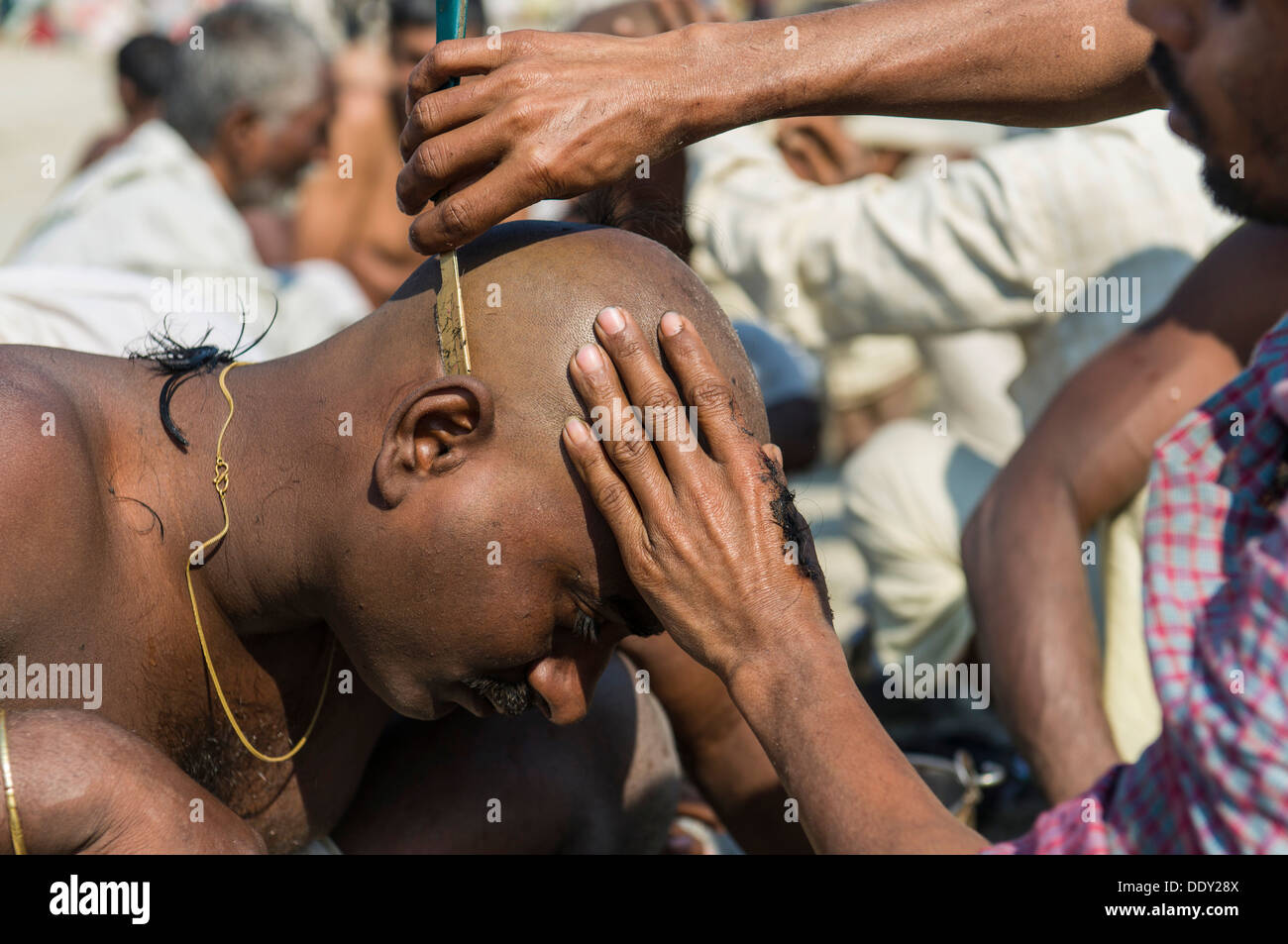 Pilgrim having his head shaved during Kumbha Mela Stock Photo