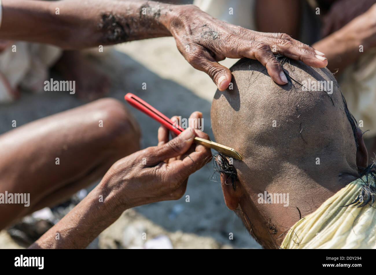 Pilgrim having his head shaved during Kumbha Mela Stock Photo