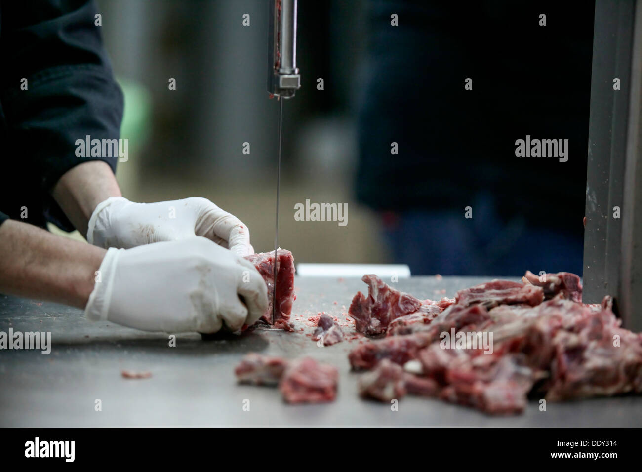 Cook uses a saw to cut meat in a restaurants kitchen Stock Photo