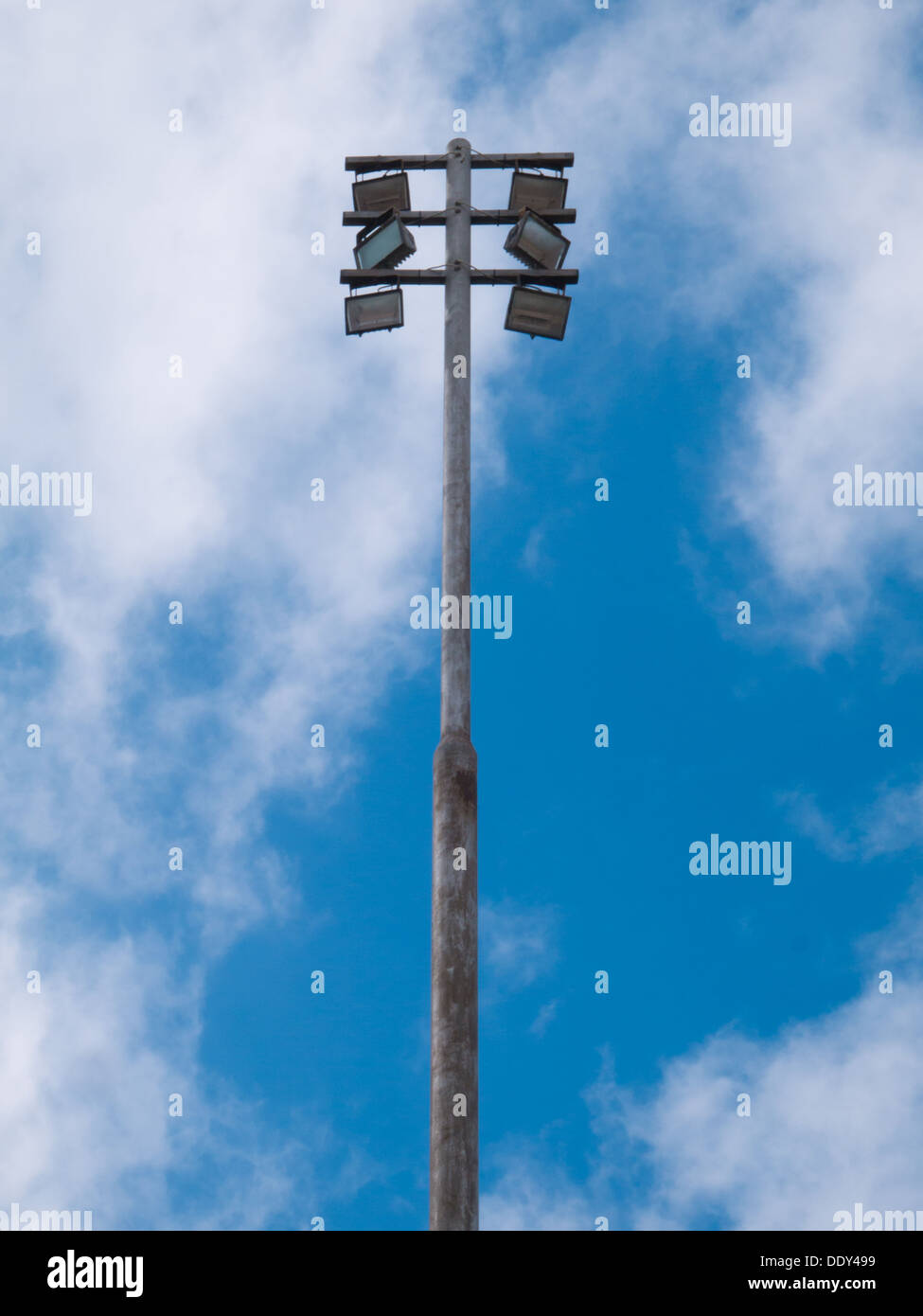 Floodlight from a football fields set against a blue sky with some white clouds. Stock Photo