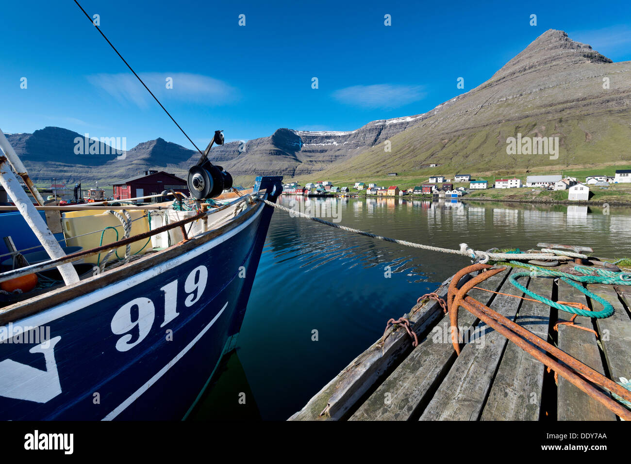 Fishing boat and rusty anchors in the harbour of Hvannasund, in front of the village of Norðdepi Stock Photo