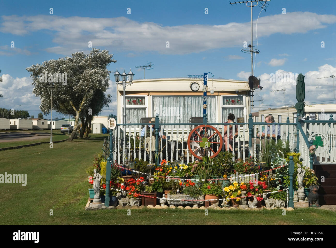 Static caravan holiday homes permanent camp site St Osyth Essex UK. Family in their front garden
