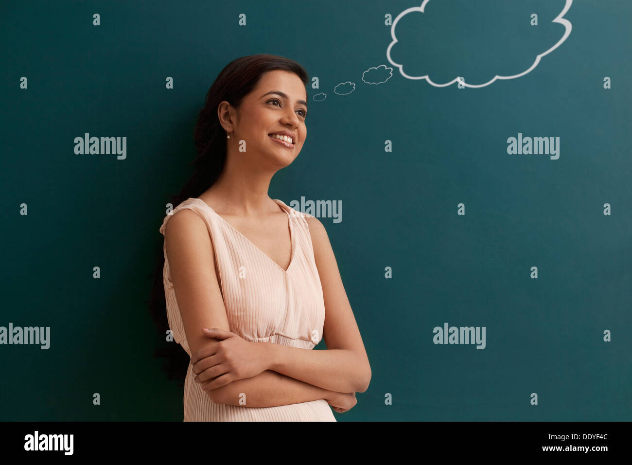 Young happy female teacher with thought bubble on chalk board Stock Photo