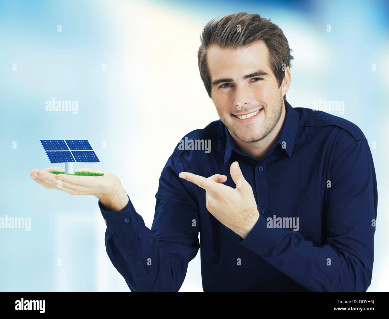 Smiling man pointing to solar cell in his hand Stock Photo