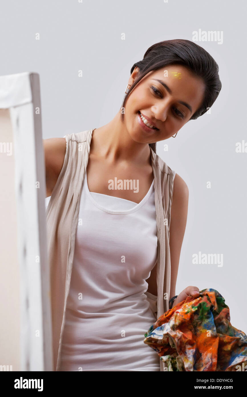 Happy female artist holding cloth while looking at painting Stock Photo