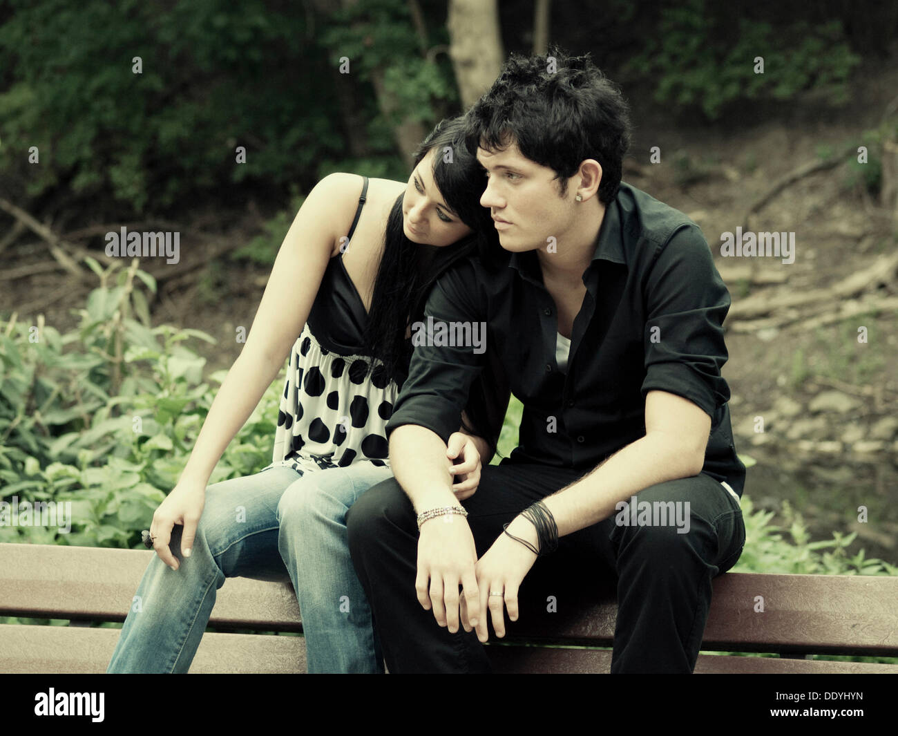 Young couple sitting on a park bench Stock Photo - Alamy