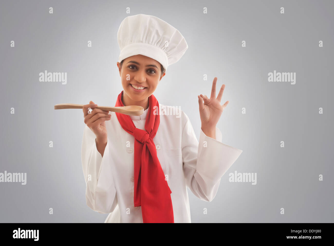 Portrait of young female chef gesturing ok sign Stock Photo