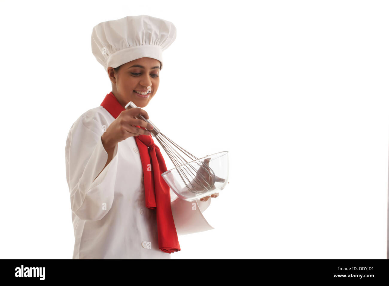 Young female chef holding mixing bowl and wire whisk isolated over white background Stock Photo