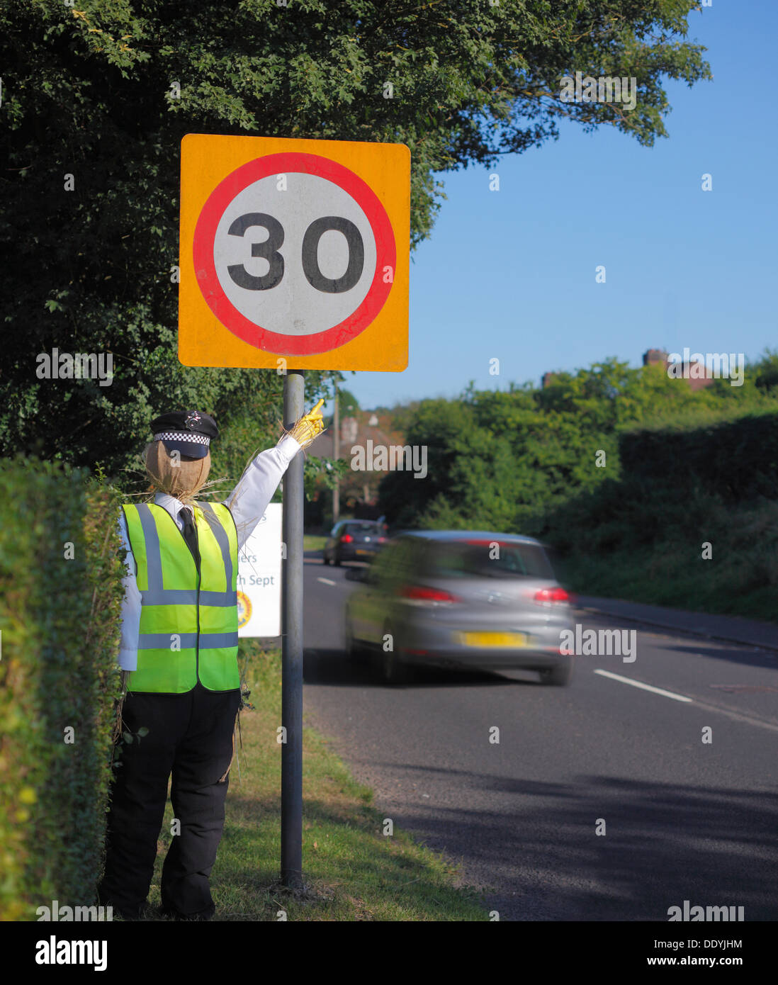 Guy mannequin dressed as a policeman pointing to a 30 mph speed sign. Stock Photo