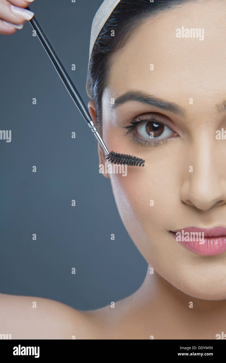 Cropped image of beautiful young woman using eyebrow tinting applicator over colored background Stock Photo