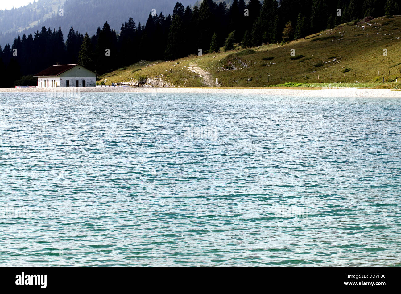 alpine hut on the shore of a beautiful alpine lake surrounded by high mountains in summer Stock Photo