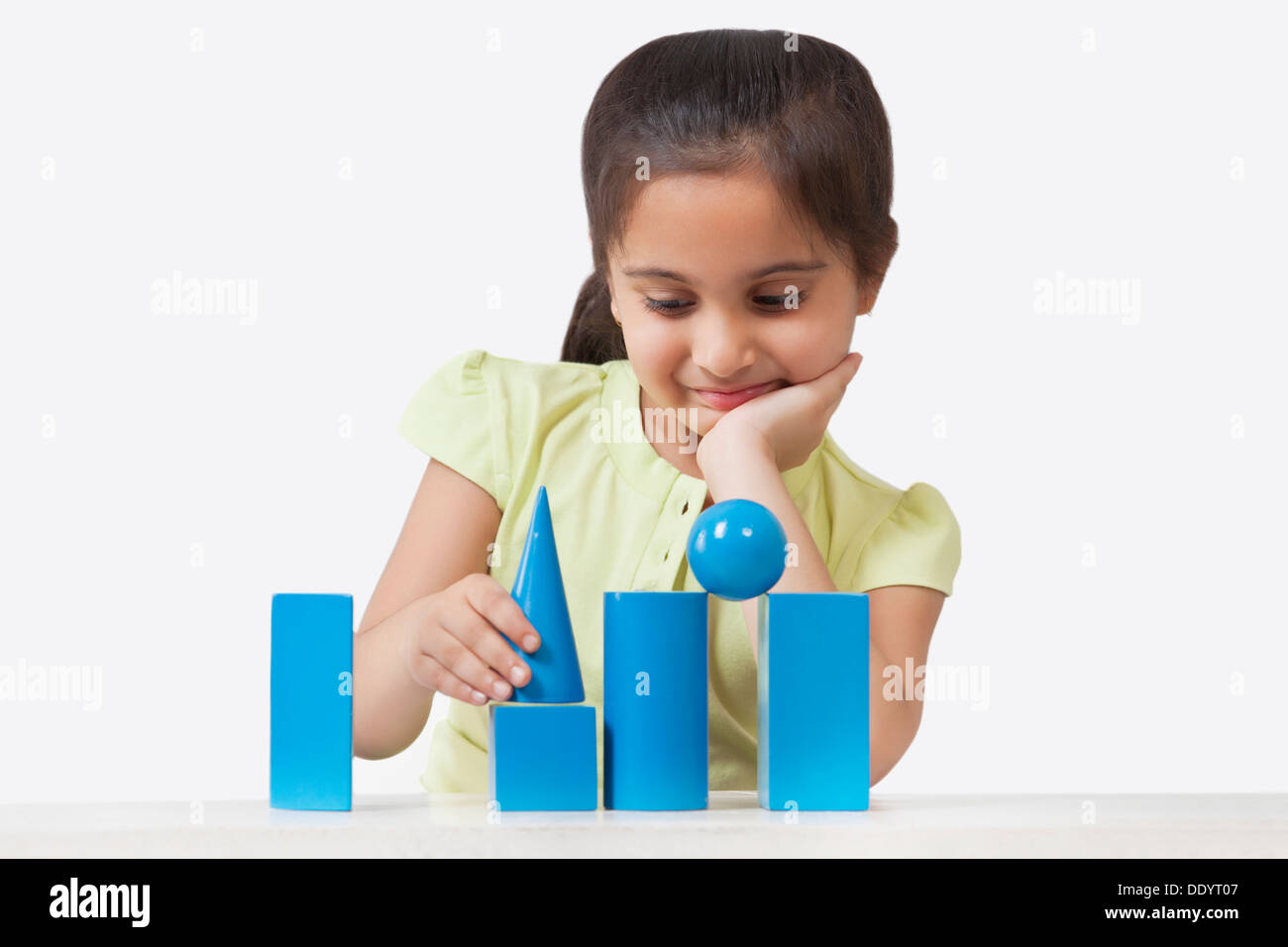 Little girl stacking geometry shaped blocks isolated over white background Stock Photo
