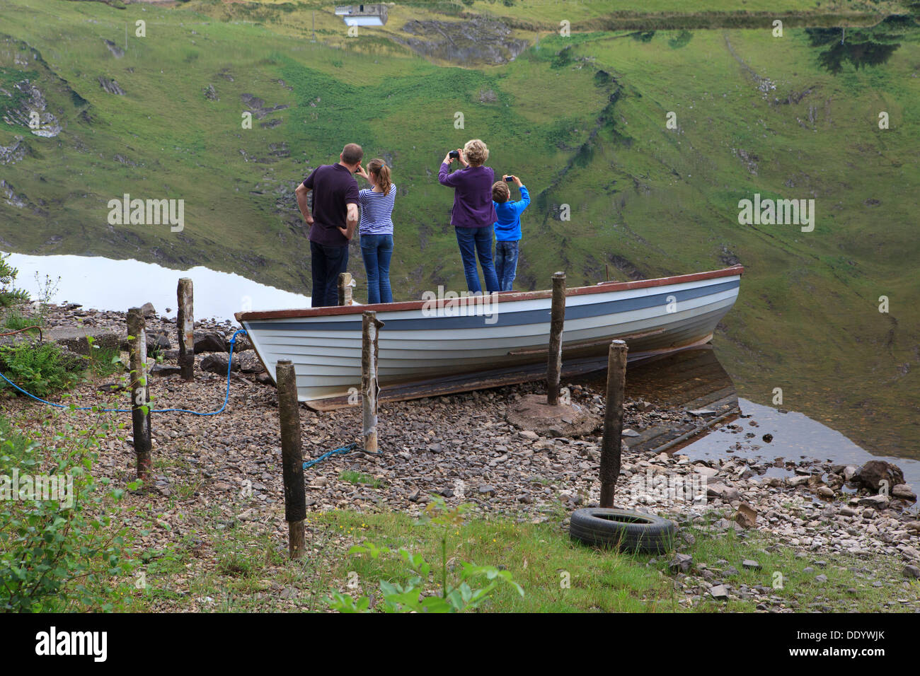 Young family making photos of the reflection on Kylemore Lough in County Galway, Ireland Stock Photo