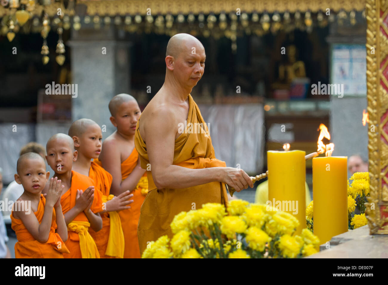 Buddhist monk and novice monks standing in a perfect line during evening prayers, Wat Phra That Doi Suthep, Chiang Mai, Thailand Stock Photo