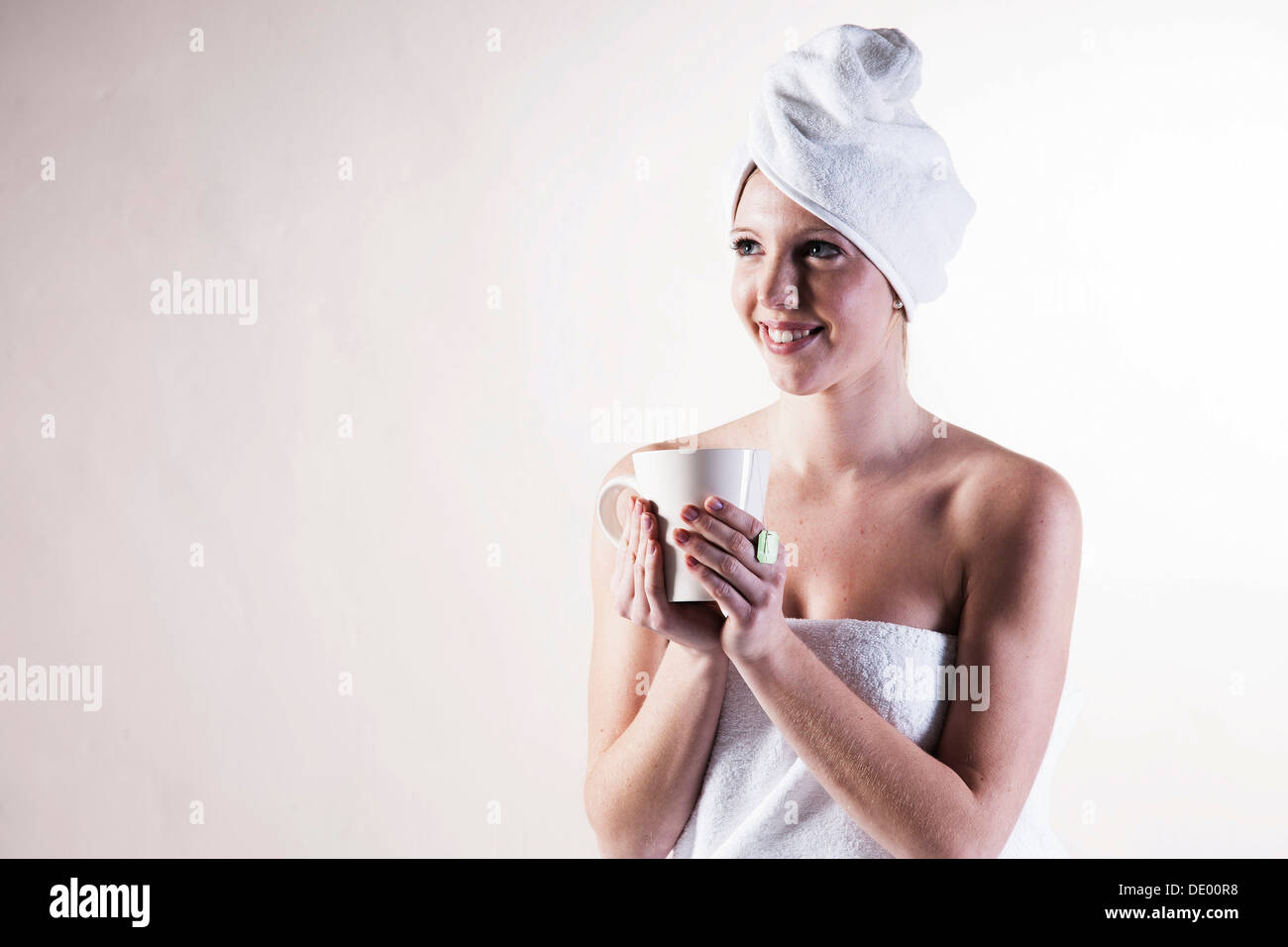Smiling young woman with a towel wrapped around her head holding a ...
