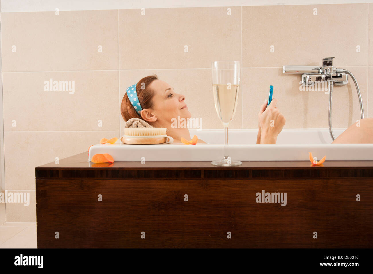 Woman using a mobile phone in the bathtub Stock Photo