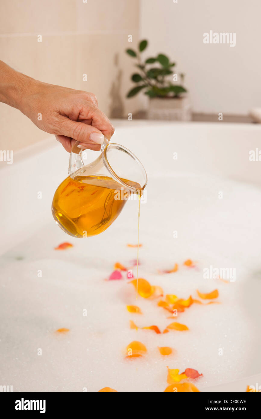 Woman pouring bath oil in a bathtub Stock Photo Alamy